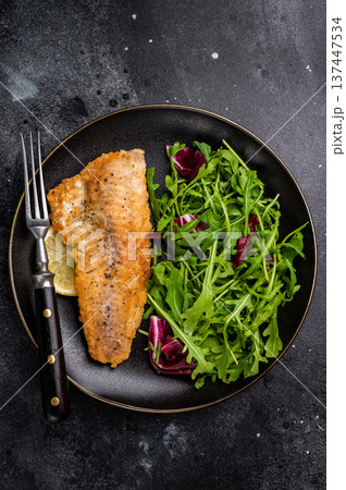 Roasted Haddock fish fillet on a plate with salad. black background. top view Roasted Haddock fish fillet on a plate with salad. black background. top view 137447534