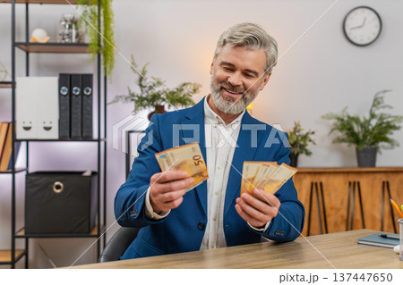 Middle-aged businessman holding euro cash counting salary income celebrating big success happiness Middle-aged businessman holding euro cash counting salary income celebrating big success happiness 137447650