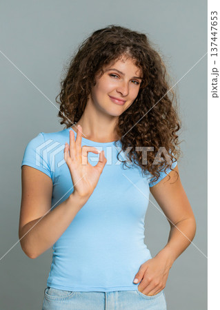 Woman smiling showing OK gesture approval satisfaction positive feedback happy pleased expression Woman smiling showing OK gesture approval satisfaction positive feedback happy pleased expression 137447653