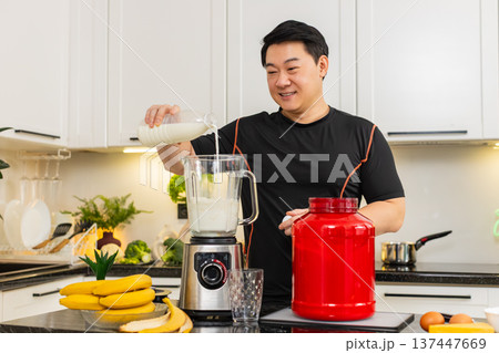 Asian man pouring milk into blender with banana cheese and protein powder preparing diet shake Asian man pouring milk into blender with banana cheese and protein powder preparing diet shake 137447669