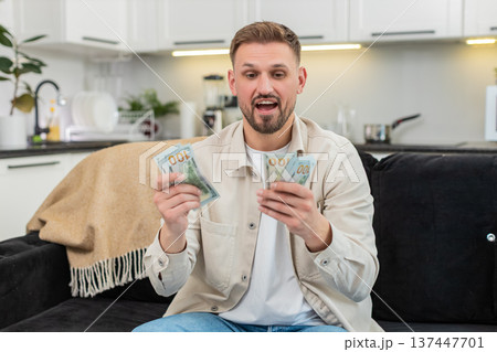 Young man counts cash dollars smiles happy with savings plans dream purchase investment bonus salary Young man counts cash dollars smiles happy with savings plans dream purchase investment bonus salary 137447701