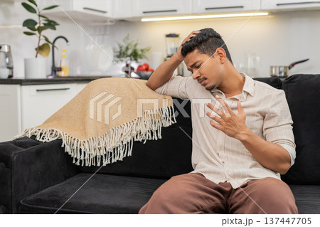 Indian man sits stressed and down after bad day holds head breathes slow and looks down in silence Indian man sits stressed and down after bad day holds head breathes slow and looks down in silence 137447705