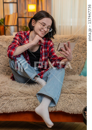 Young woman laughing while listening to podcast on smartphone reacting joyfully funny conversation 137447736
