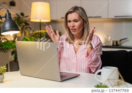 Adult woman freelancer reads tender loss message on laptop frowns shakes head sighs disappointment Adult woman freelancer reads tender loss message on laptop frowns shakes head sighs disappointment 137447769