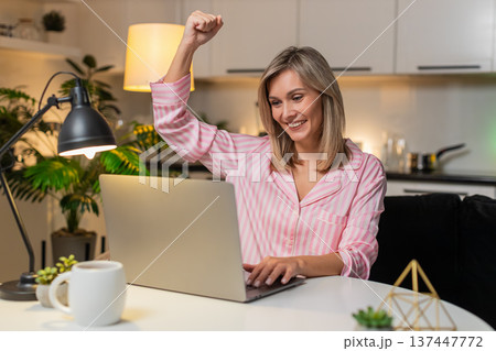 Adult woman receives bonus notification on laptop smiles celebrates raises hand excited jackpot win 137447772