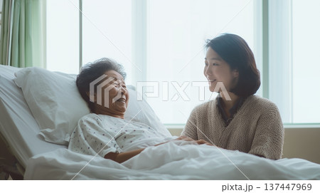 ベッドで寝ているシニア女性と介護する女性 137447969