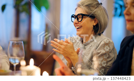 Senior woman laughing and clapping at dinner party 137448423
