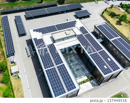 Aerial view of building with solar panels on a roof and parking space with solar canopies. 137449538