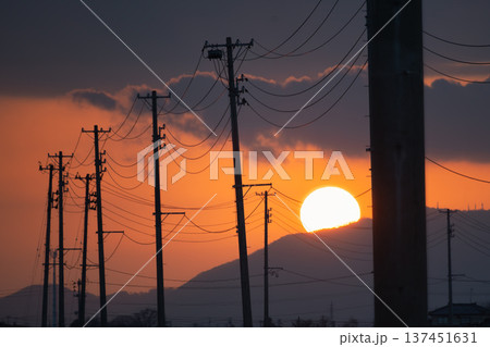 電柱の列と沈みゆく大きな夕日が作るノスタルジックな夕焼け空 電柱の列と沈みゆく大きな夕日が作るノスタルジックな夕焼け空 137451631
