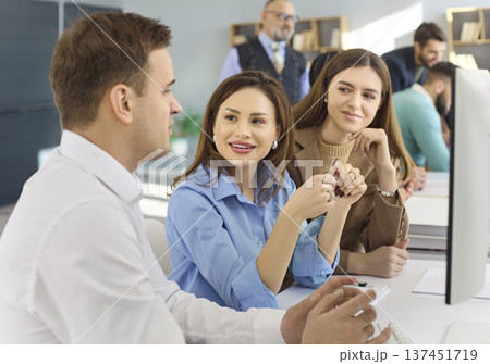 Adult students collaborating at computers during modern office classroom training 137451719