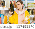 Girl customer in supermarket examines oil, chooses food-stuff in grocery 137453370