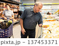 Elderly male customer looking around in dairy section of supermarket 137453371