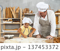 Father and daughter roll out dough together to make delicious bread 137453372
