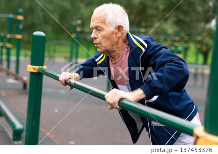 Senior european man doing push-ups outdoors 137453376
