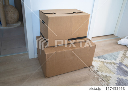 Cardboard moving boxes stacked on floor in minimalist home interior 137453468