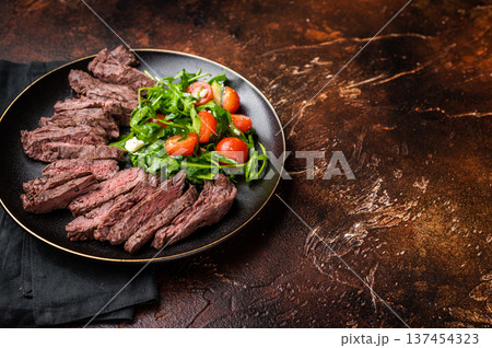 Grilled and sliced Beef Denver strip Steak on a plate with salad. brown background. top view 137454323