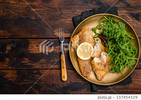 Roasted Pollock fish fillet on a plate with salad. wooden background. top view Roasted Pollock fish fillet on a plate with salad. wooden background. top view 137454329
