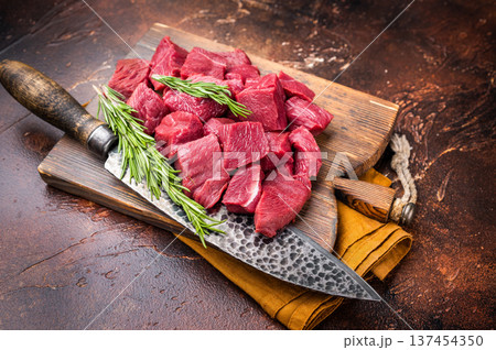 Diced Raw Venison meat, fresh Wild Roe Deer Game Meat on butcher cutting board. brown background. top view Diced Raw Venison meat, fresh Wild Roe Deer Game Meat on butcher cutting board. brown background. top view 137454350