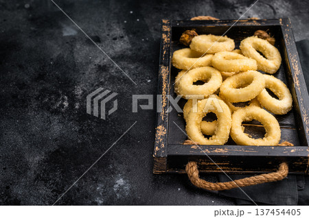 Raw squid rings with breading, uncooked calamari snack. black background. top view Raw squid rings with breading, uncooked calamari snack. black background. top view 137454405