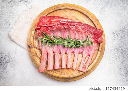 Uncooked rack of lamb, raw mutton chops on wooden board. grey background. top view Uncooked rack of lamb, raw mutton chops on wooden board. grey background. top view 137454429