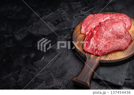 Butcher board with raw beef cheeks, uncooked meat. black background. top view 137454436