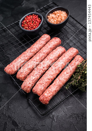 Uncooked Raw Cevapcici Sausage, fresh Cevapi from mince beef and pork meat on a rack. black background. top view 137454443