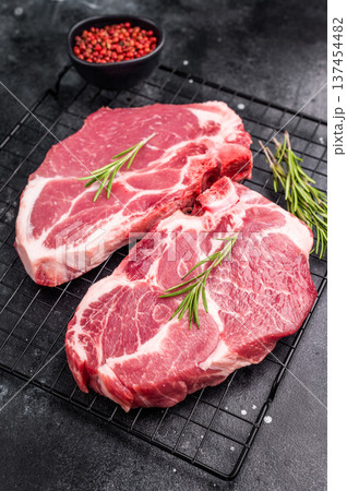 Raw pork tender steak, fresh neck meat with herbs on steel rack. black background. top view Raw pork tender steak, fresh neck meat with herbs on steel rack. black background. top view 137454482