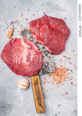 Raw beef cheeks on butcher meat cleaver. grey background. top view Raw beef cheeks on butcher meat cleaver. grey background. top view 137454495