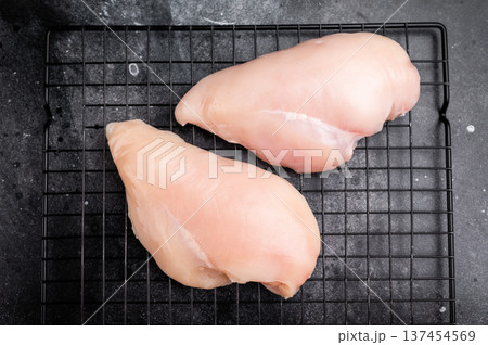 Fresh chicken breasts, beautifully displayed, showcasing their tender texture. Perfect for marinating and cooking your favorite dishes. black background. top view 137454569