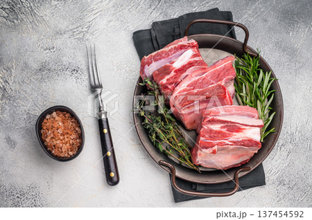 Raw lamb Riblets, fresh mutton meat with rib bone. grey background. top view Raw lamb Riblets, fresh mutton meat with rib bone. grey background. top view 137454592