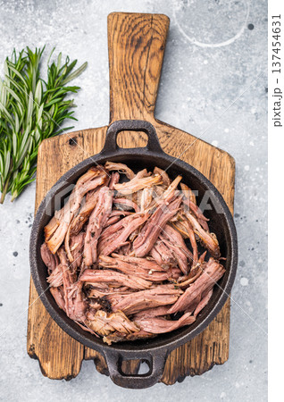 Savory pulled beef brisket served in a skillet, dipping creating an appealing and mouthwatering culinary scene. grey background. top view Savory pulled beef brisket served in a skillet, dipping creating an appealing and mouthwatering culinary scene. grey background. top view 137454631