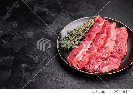 Raw sliced horse meat steaks presented with herbs and spices, inviting creativity in the kitchen for those seeking bold flavors and unique dining experiences. black background. top view 137454636