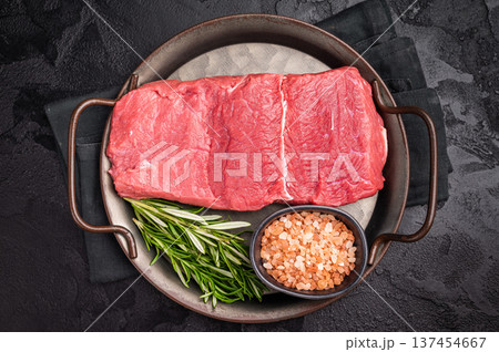 A selection of raw bison steaks arranged artfully, emphasizing their quality and texture, inviting culinary creativity in the kitchen. black background. top view A selection of raw bison steaks arranged artfully, emphasizing their quality and texture, inviting culinary creativity in the kitchen. black background. top view 137454667