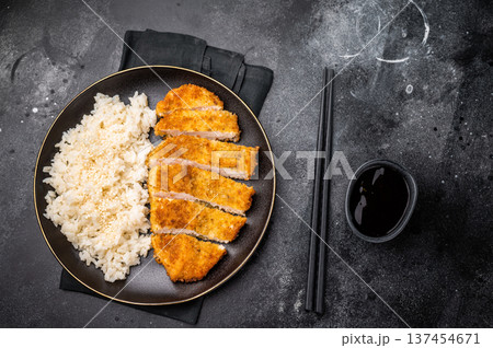 Delicious katsu style dish, featuring a perfectly cooked chicken meat cutlet served alongside steamed rice for a balanced meal. black background. top view Delicious katsu style dish, featuring a perfectly cooked chicken meat cutlet served alongside steamed rice for a balanced meal. black background. top view 137454671