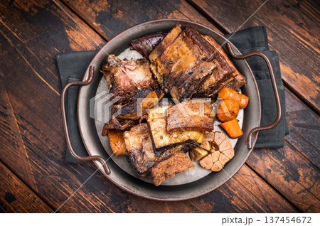 Grilled beef short ribs glistening under natural light, accompanied by fresh greens and spices, capturing the essence of gourmet comfort food. wooden background. top view 137454672