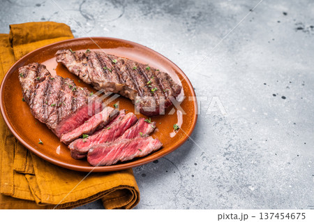 Tender flat iron steak, grilled to enhance its natural flavors and tenderness. grey background. top view Tender flat iron steak, grilled to enhance its natural flavors and tenderness. grey background. top view 137454675