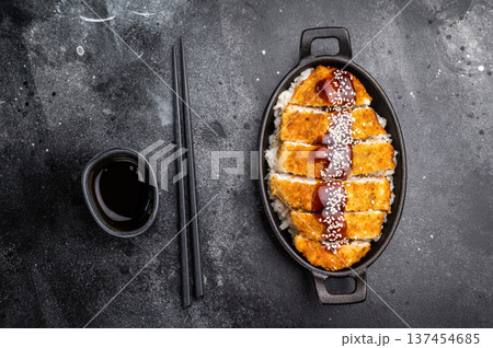 Crunchy Japanese cutlet katsu, seasoned to perfection and served with a side of rice and sauce. black background. top view 137454685