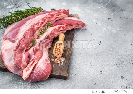 Uncooked lamb belly breast cut with rosemary thyme and salt on wooden board light background butcher style preparation with copy space 137454762