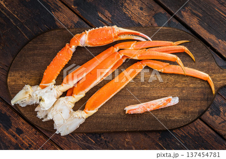 Steamed king crab legs with lemon rosemary and butter sauce on wooden board dark background copy space 137454781