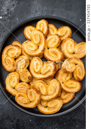 Golden palmier puff pastry cookies in black bowl on dark stone background copy space sweet bakery dessert top view Golden palmier puff pastry cookies in black bowl on dark stone background copy space sweet bakery dessert top view 137454785
