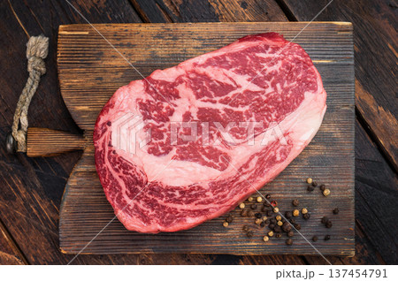 Fresh raw ribeye steak, marbled rib fillet beef cut, gourmet steakhouse meat on rustic wood surface with herbs and copy space 137454791