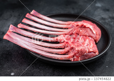 Raw lamb rack bone in meat on cast iron pan stone background top view culinary ingredient with copy space Raw lamb rack bone in meat on cast iron pan stone background top view culinary ingredient with copy space 137454822