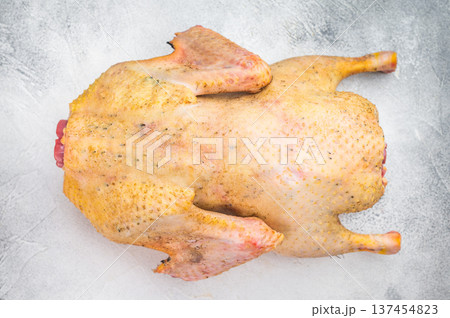 Uncooked whole goose poultry game meat with cleaver and fork on light gray background. Gamebird ingredient for rustic cuisine. Uncooked whole goose poultry game meat with cleaver and fork on light gray background. Gamebird ingredient for rustic cuisine. 137454823