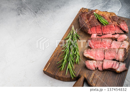 Pan fried Cooked beef chuckeye steak sliced and served with herbs and pink salt. Rustic beef dish with copy space top view. 137454832