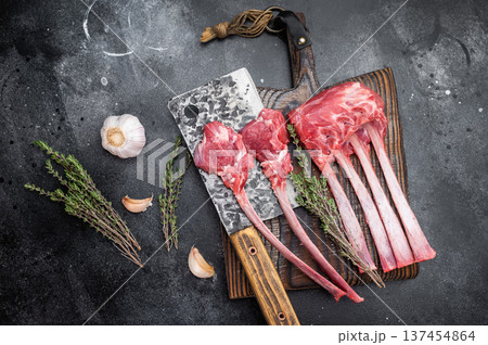 Fresh uncooked lamb chops and ribs with thyme on cutting board dark textured background overhead meat preparation 137454864