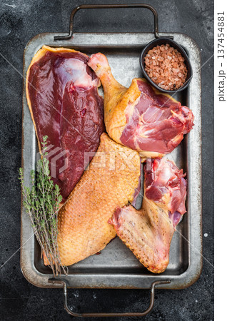Raw duck meat assortment with skin and trimmings on metal tray. Gamebird poultry game meat food still life top view. 137454881