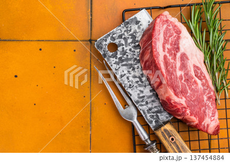 Fresh raw beef chuck eye roll steak on metal rack with butcher tools and herbs. Premium marbled beef meat for cooking. 137454884