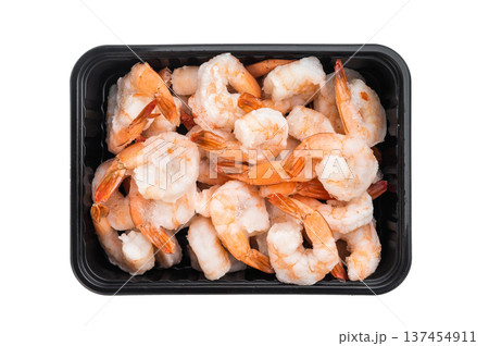 Frozen cooked shrimp with tails in black tray from super market isolated on white background. Icy seafood protein ingredient closeup. 137454911