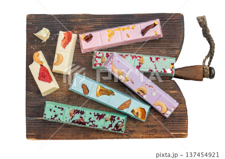 Assorted colorful craft chocolate bars with dried fruits and nuts on rustic wooden boards over light textured background top view Assorted colorful craft chocolate bars with dried fruits and nuts on rustic wooden boards over light textured background top view 137454921