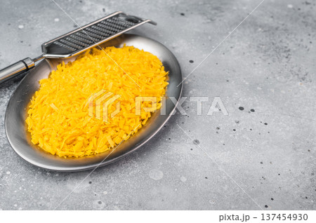 Pile of grated cheddar cheese in bowl on stone backdrop cooking ingredient with copy space for food banners and menus Pile of grated cheddar cheese in bowl on stone backdrop cooking ingredient with copy space for food banners and menus 137454930